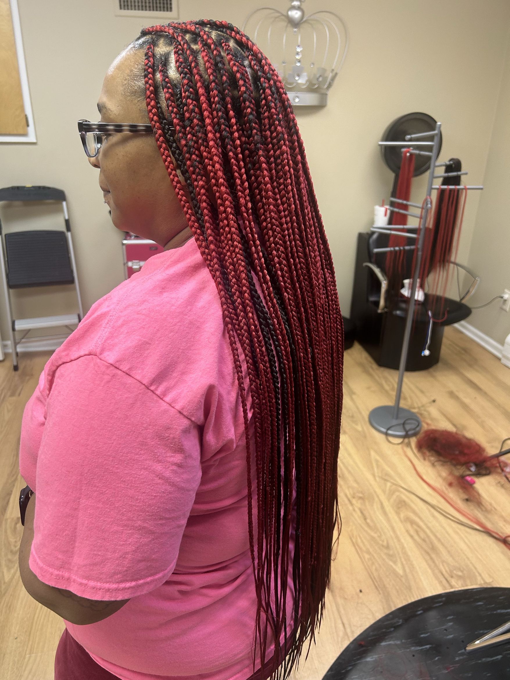 Long burgundy braids styled by Crown Solutions in Lansing